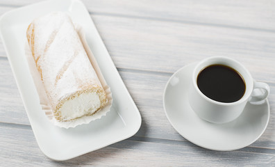 Cream pie served on tray next to coffee on wooden table. Food