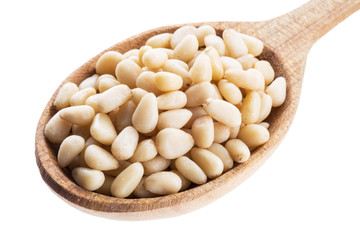 Pine nuts in the wooden spoon. White background.