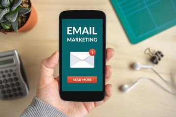 Hand holding smart phone with email marketing concept on screen. All screen content is designed by me. Flat lay