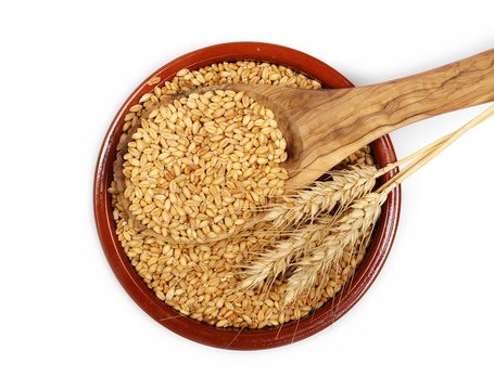 Wheat ears and grains with wooden spoon in porcelain bowl isolated on white background, top view