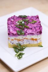 Russian food: holiday herring salad with vegetables close-up on the table