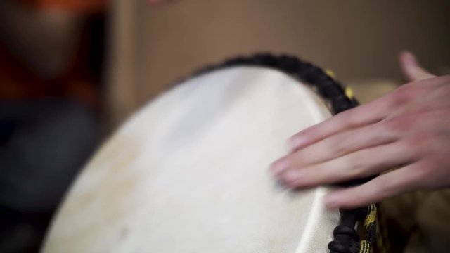 Close up of hands of a black man playing a drum. Clip. Drummer plays on small African drum, closeup photo with selective focus