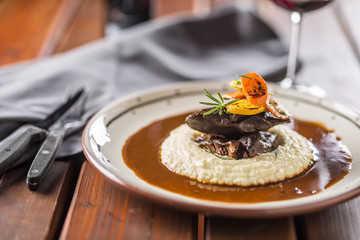 Roasted or confit beef steak mashes potatoes wegetable and sauce with red wine in pub or restaurant.