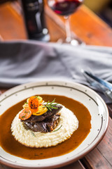 Roasted or confit beef steak mashes potatoes wegetable and sauce with red wine in pub or restaurant.