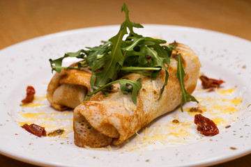 Delicious pancakes with arugula on a white plate