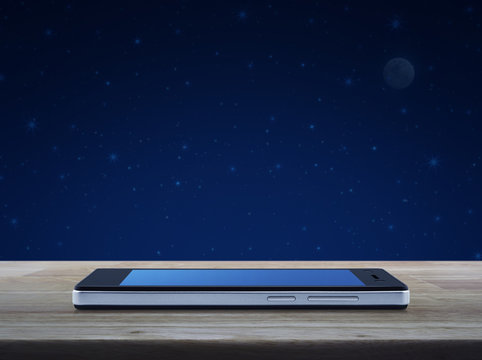 Modern Smart Phone With Blank Blue Screen On Wooden Table Over Fantasy Night Sky And Moon