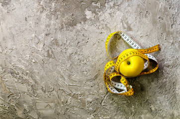 Obraz premium Yellow apple with measuring tape on concrete background. Top view