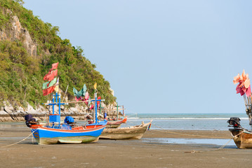 Naklejka na ściany i meble Fishing boats aground on the beach over sunny sky at Prachuap Khiri Khan, Thailand.