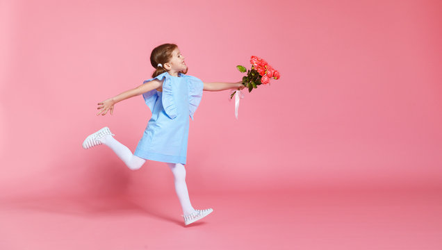 funny child girl runs and jumps with bouquet of flowers on colored background.
