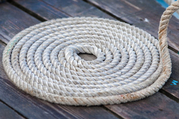 Roll of rough mooring rope on wooden dock