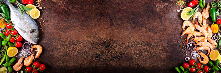 Fresh fish, shrimps with herbs, spices and vegetables on dark vintage background. Healthy food, diet or cooking concept. Banner
