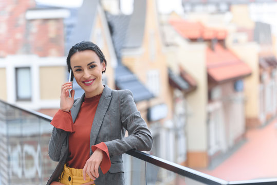 Attractive Stylish Woman Standing On Balcony And Talking By Smartphone