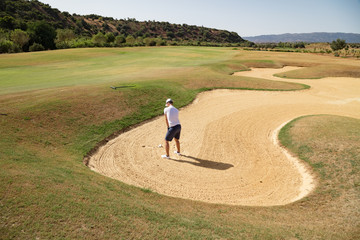 Golf player in sand trap hitting the ball