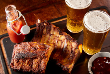 Two spicy barbecued ribs portions with cold beer