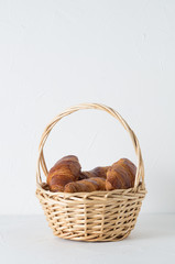fresh pastries: croissants in a wicker basket on a white background