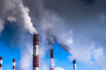 Dramatic scene - the smoke coming from the pipe covering the blue sky. The concept of global warming