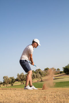 Golf player hitting golf ball in golf course