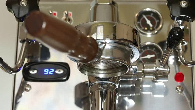 Brewing coffee at home using a nice stainless steeel coffee machine and bottomless portafilter. Barista making coffee at home.