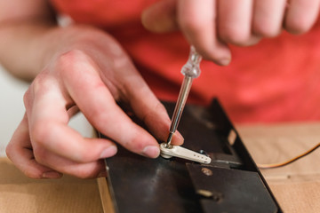 White person tightens a screw with a screwdriver