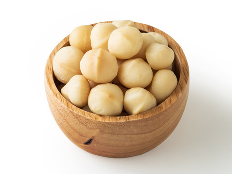 Macadamia nuts in wooden bowl on white background