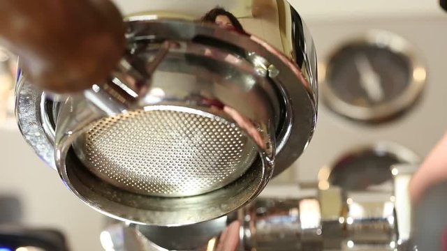 Brewing coffee at home using a nice stainless steeel coffee machine and bottomless portafilter. Barista making coffee at home.
