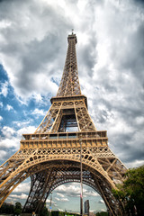 Fototapeta na wymiar Eiffel Tower in Paris, France. Tower on cloudy sky. Architecture structure and design concept. Summer vacation in french capital