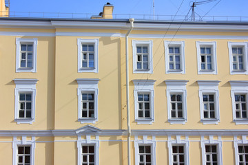Obraz premium Architecture Detail of Old Historical Building Front. Classical Minimalist Exterior Facade with Squared Windows and Simple Ornamental Decor on Yellow Walls. View of Modern Apartment Building Structure
