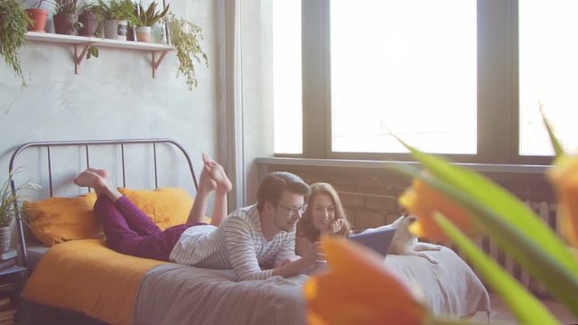 Happy young couple with french dog with laptop at home. Slow motion