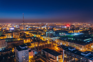 Aerial view of night Voronezh downtown. Voronezh cityscape at blue hour. Urban lights, modern houses, television tower, stadium