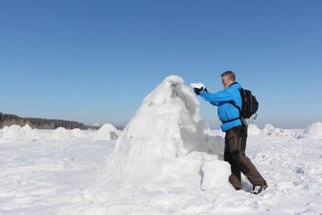 Man building an igloo on a snowy reservoir in winter, Novosibirsk, Russia