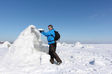 Man building an igloo on a snowy reservoir in winter, Novosibirsk, Russia