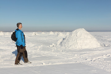 Man walking near an igloo on a snowy reservoir in winter, Novosibirsk, Russia