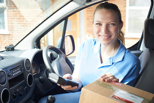 Portrait Of Female Courier In Van Delivering Package To Domestic House