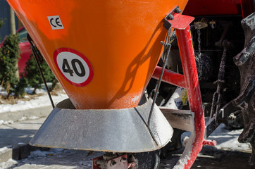Close-up of container  for spilling salt.  Standing  snow cleaning machine  covered with salt and snow at sunny day