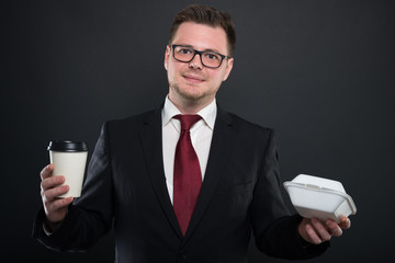 Portrait of business man holding coffee and lunchbox.