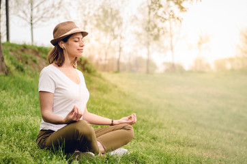 Young beautiful woman meditating in the nature in the morning