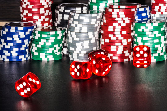 a pile of poker chips next to red, dice on a blackboard, background image