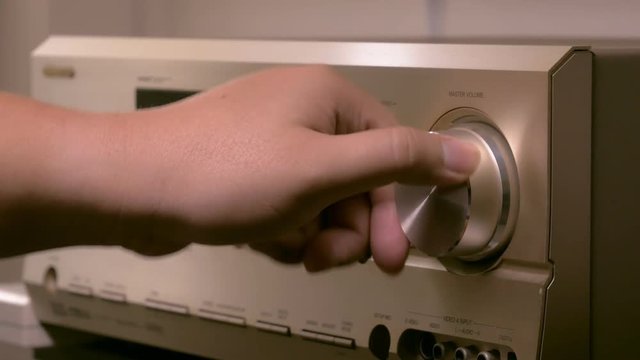 Men's hands are changing the volume in the amplifier of the home theater.