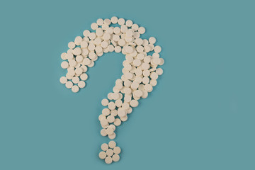 White tablets, laid in the form of a question mark, a question mark with a medical bias.