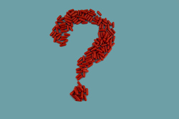 Medical question of red capsules with medicine on a blue background.