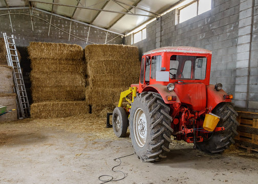 tractor in a shed with haystacks