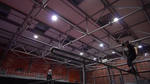 A girl sits and watches people perform tricks in an extreme park, slow motion