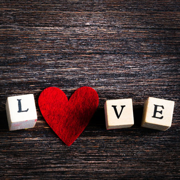 Wood cubes with inscription Love you and red textile heart on wooden background. Free space for your text.