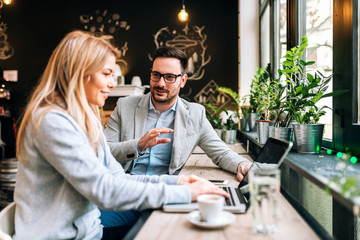 Young man flirting with a woman who is working on a laptop at the cafe.