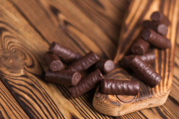 Lot of yummy chocolate candies scattered on wooden cutting board and old weathered wooden table