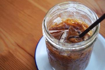 Soft Drink, Summer refreshment drinks, glass of iced coffee with copy space placed on white plate and both placed on wooden table 