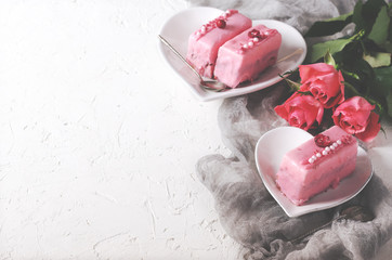 Valentine pink cakes and two teaspoons on white concrete background. Free space for your text. Toned effect.