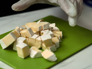 Step-by-step preparation of black designer cake. The confectioner prepares cream with cheese brie for cake.