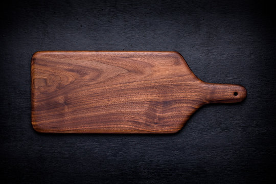 Walnut handmade wood cutting board on black wooden board
