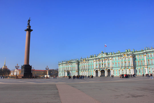 Palace Square with Winter Palace Building and Alexander Column in Saint Petersburg, Russia. Scenic Wallpaper of Main City Square Architecture on Sunny Summer Day against Empty Blue Sky Background.